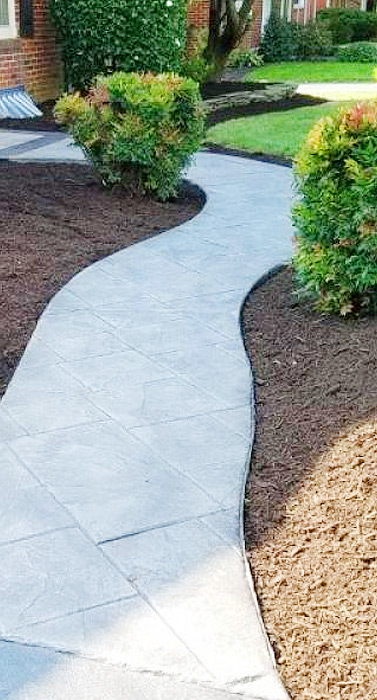 A walkway with cement and mulch around it.