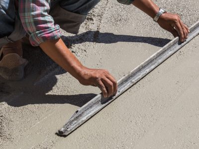 A person measuring the length of concrete