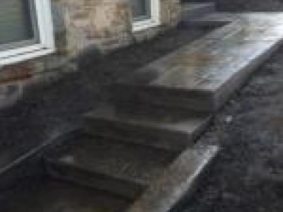 A concrete walkway with steps leading to the house.