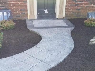 A walkway in front of a house with a door.